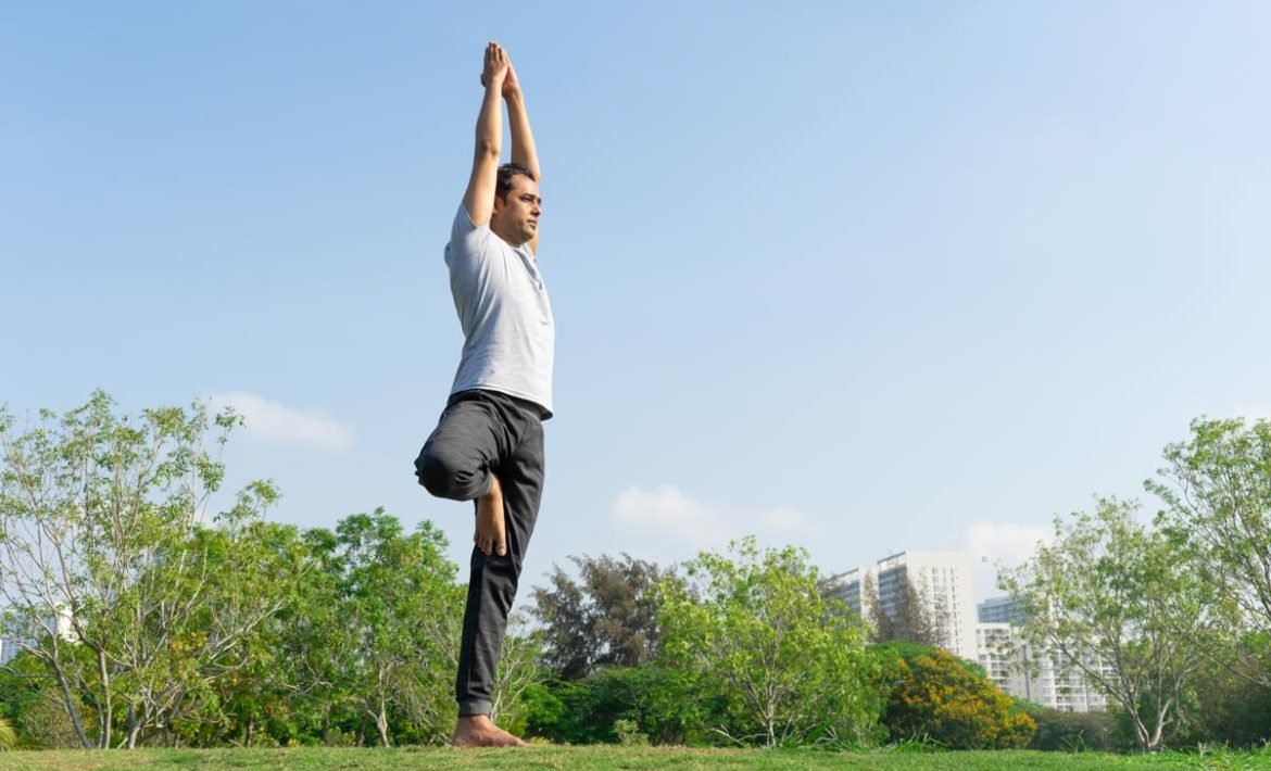 A person practicing Vrikshasana Tree Pose with proper standing alignment and focused gaze on a blue yoga mat.