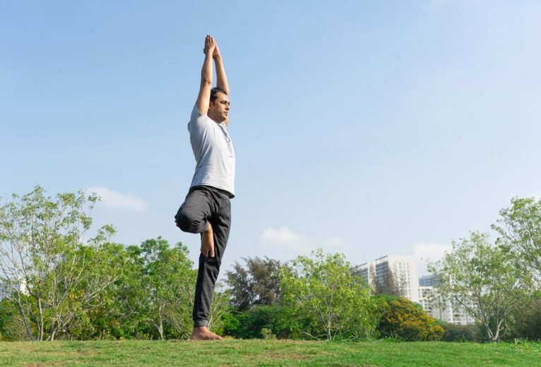 A person practicing Vrikshasana Tree Pose with proper standing alignment and focused gaze on a blue yoga mat.
