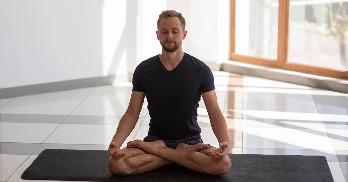 A yoga practitioner keeping a long, upright spine and level hips while demonstrating correct leg alignment in Padmasana.