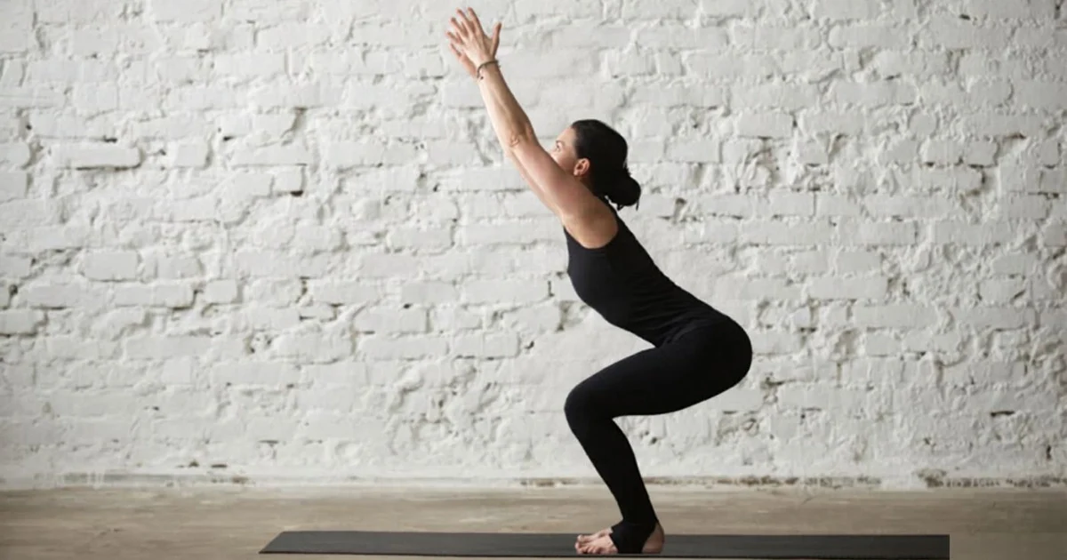 A yoga practitioner keeping their spine long and weight back in their heels while practicing proper alignment in Utkatasana.