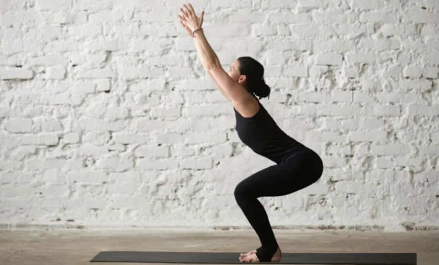 A yoga practitioner keeping their spine long and weight back in their heels while practicing proper alignment in Utkatasana.