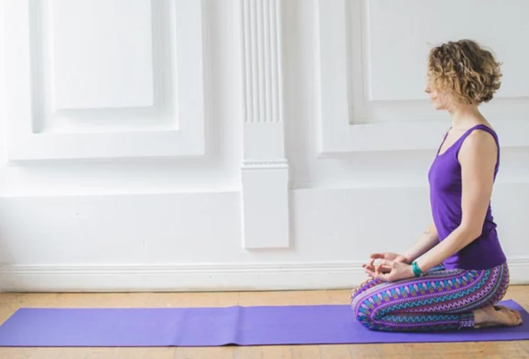 A yoga practitioner keeping an upright spine and stacked joints while demonstrating proper alignment in Vajrasana Thunderbolt Pose.
