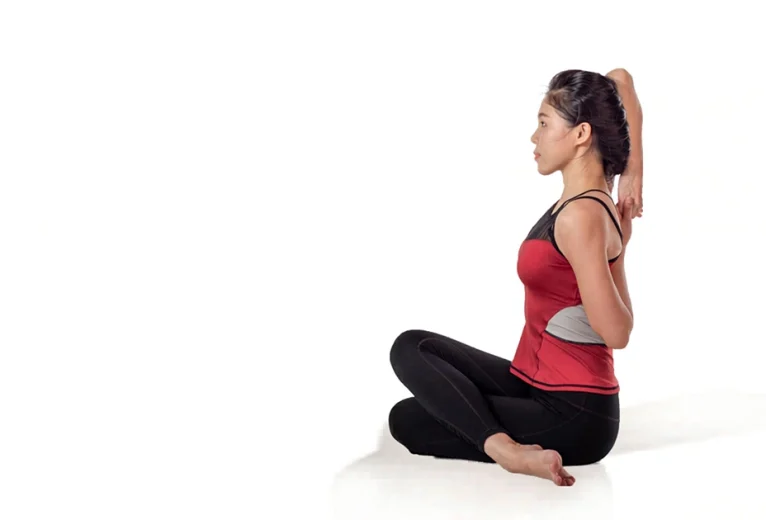 A yoga practitioner demonstrates proper spine elongation and stacked knee alignment in Gomukhasana.