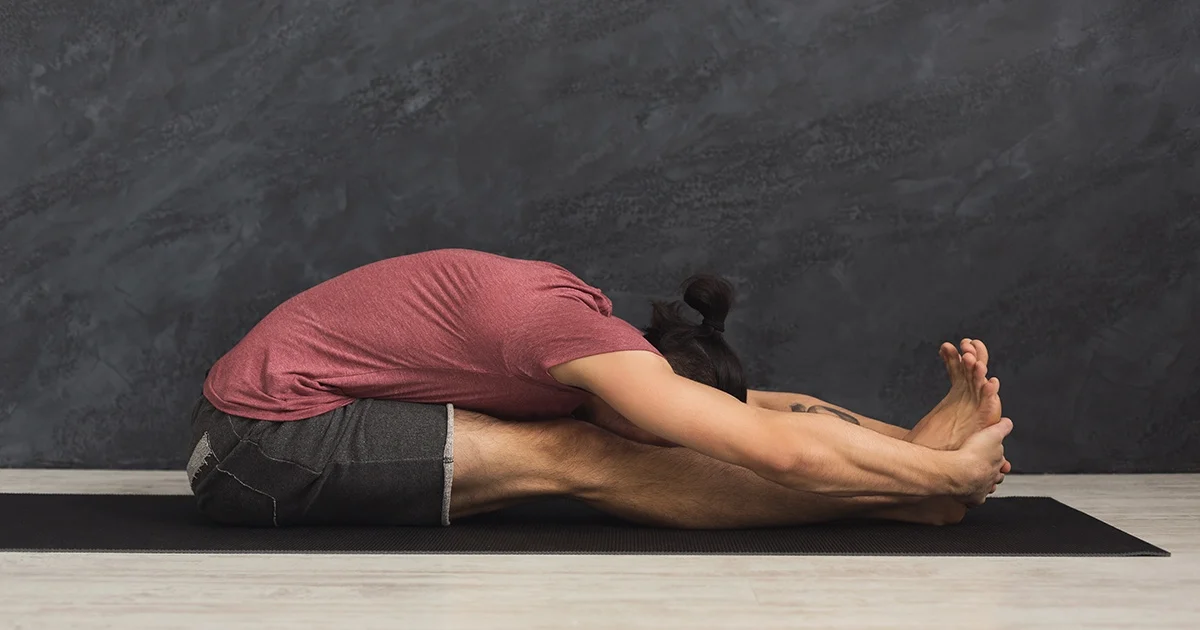 A yoga practitioner demonstrates proper pelvic tilting and safe spinal lengthening while holding Paschimottanasana.