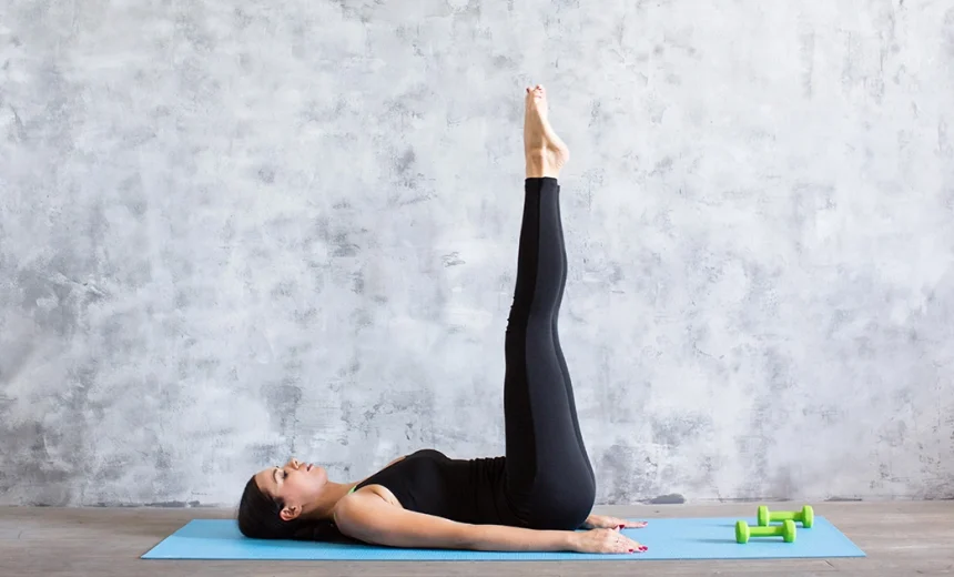 A yoga practitioner demonstrates a flat lower back and legs extended vertically at a ninety degree angle in Ardha Halasana.