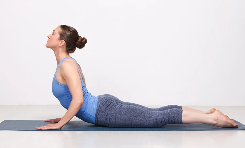 A yoga practitioner keeping her shoulders drawn back away from her ears while showing correct alignment in Bhujangasana.