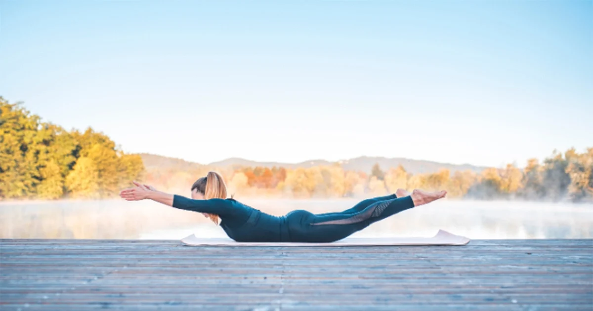 A yoga practitioner demonstrates elongated arms and legs lifted simultaneously in a balanced Viparita Shalabhasana arc.