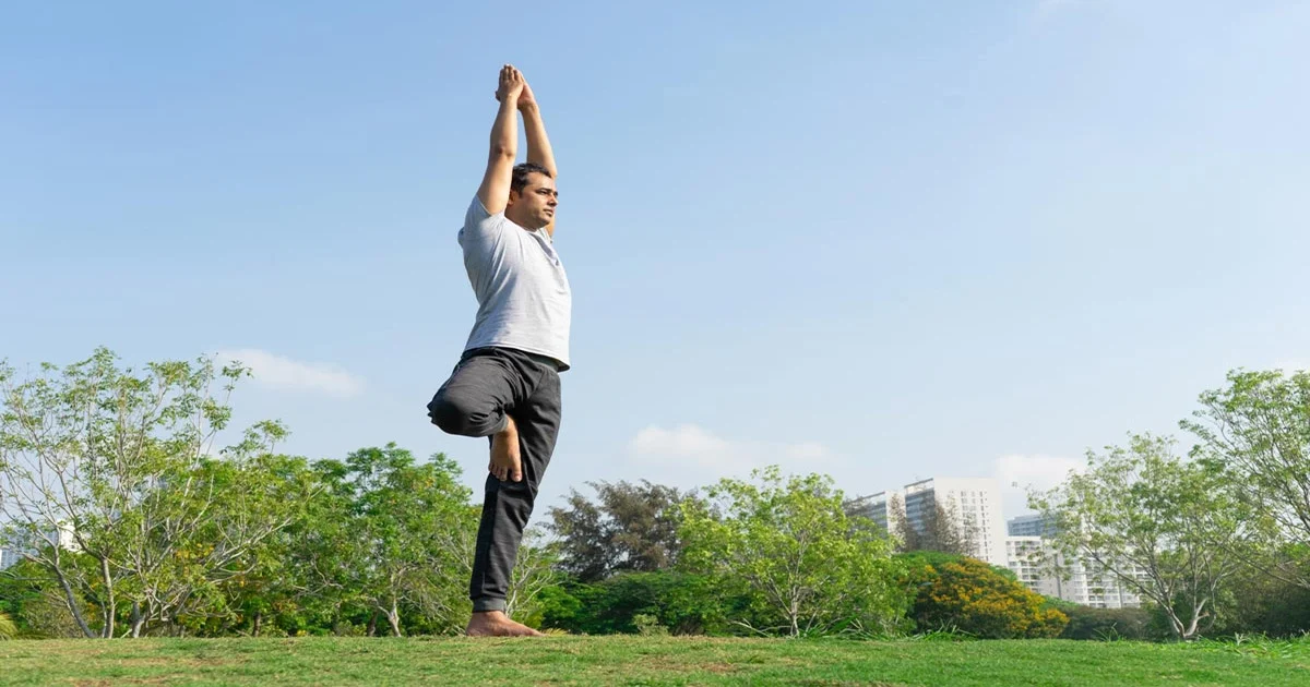 A yoga practitioner keeping proper alignment in Vriksasan Tree Pose by balancing on one leg with arms extended on a mat.