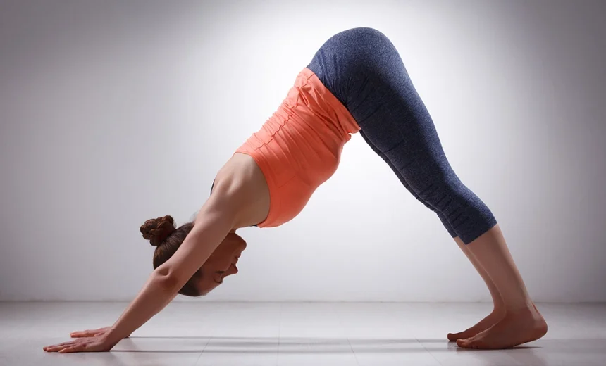 A yoga practitioner demonstrates correct alignment in Adho Mukha Svanasana, extending the spine and heels while pressing firmly through the palms.