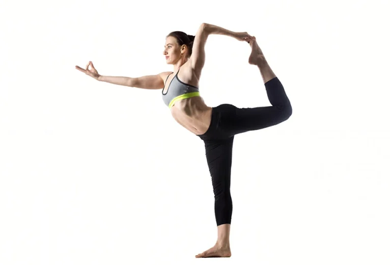 A yoga practitioner demonstrates perfect alignment in Natarajasana, focusing on a single point while extending the back leg into a graceful arc.