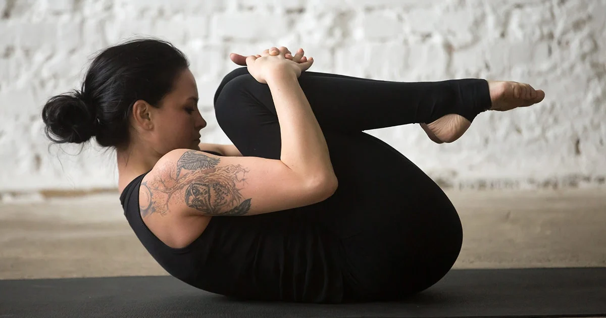 A yoga practitioner demonstrates a flat lower back and relaxed shoulders while holding Pawanmuktasana.