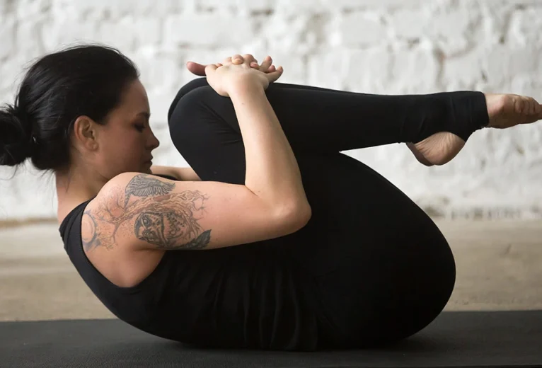 A yoga practitioner demonstrates a flat lower back and relaxed shoulders while holding Pawanmuktasana.