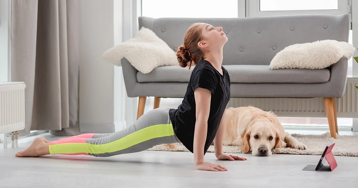 A practitioner demonstrates correct alignment in Urdhva Mukha Svanasana with active thighs lifted off the mat and shoulders stacked above the wrists.