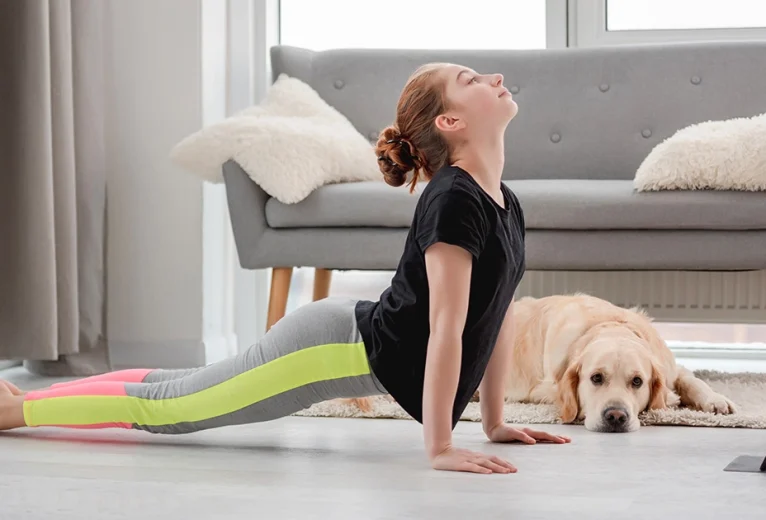 A practitioner demonstrates correct alignment in Urdhva Mukha Svanasana with active thighs lifted off the mat and shoulders stacked above the wrists.